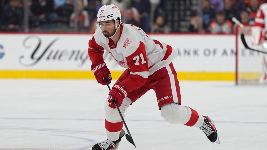 Dylan Larkin and Connor Hellebuyck during NHL game action.