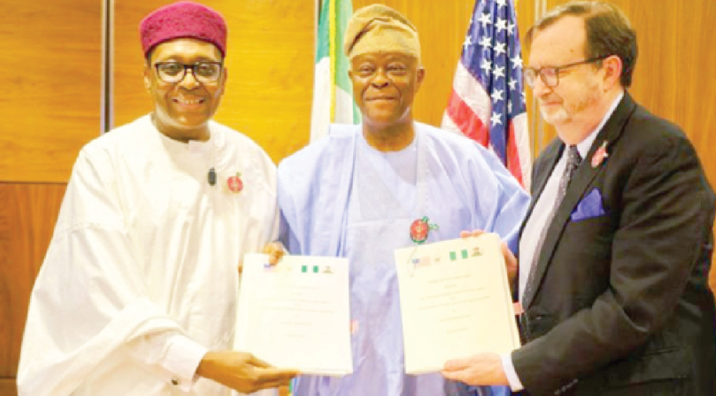 Bilateral agreement documents and flags representing the United States and Nigeria on a desk.